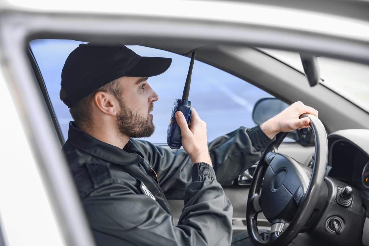 Security officer coordinating property coverage from a patrol vehicle